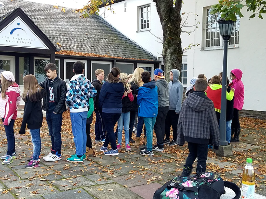 Gruppe steht im Kreis vor dem Gebäude der Jugendherberge.